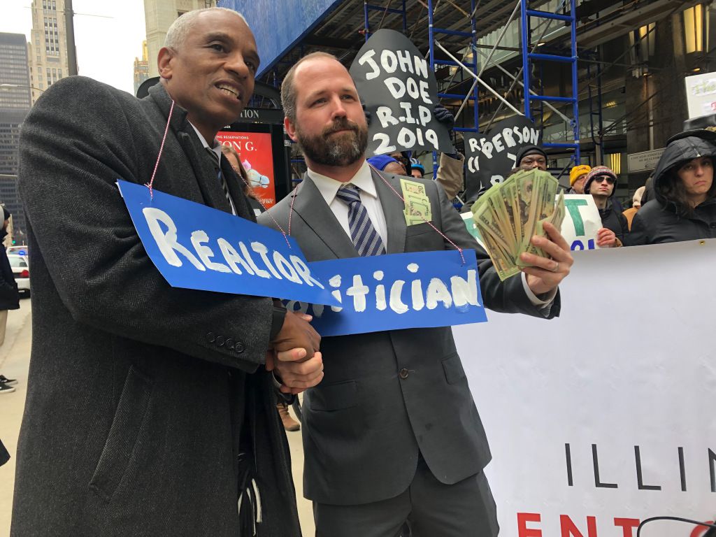 A Lift the Ban Coalition rally in support of rent control took place outside the Chicago Association of Realtors office on Friday. These two men dressed in costume, throwing fake money between a “realtor” and “politician.” | Alex Arriaga