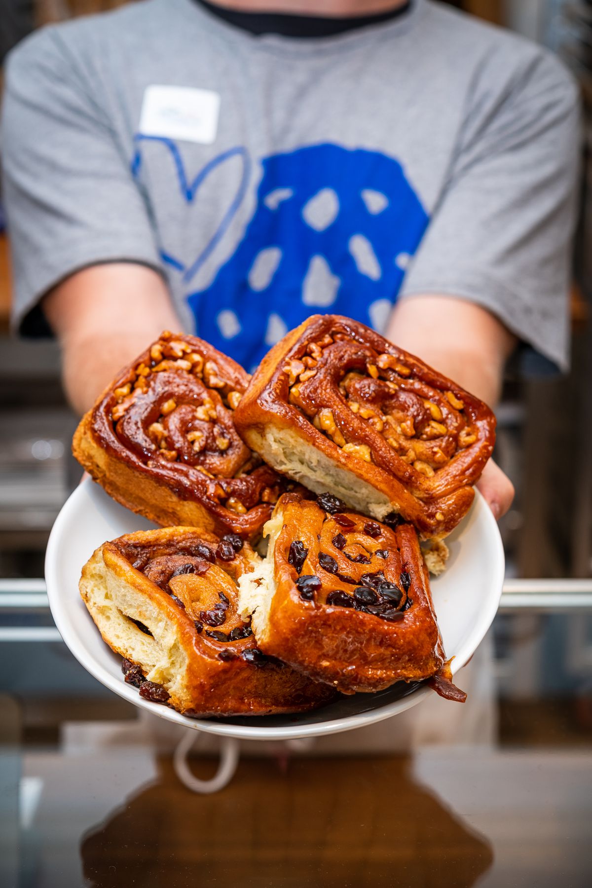 A staff member at Levain presents a plate filled with swirled raisin and walnut sticky buns.