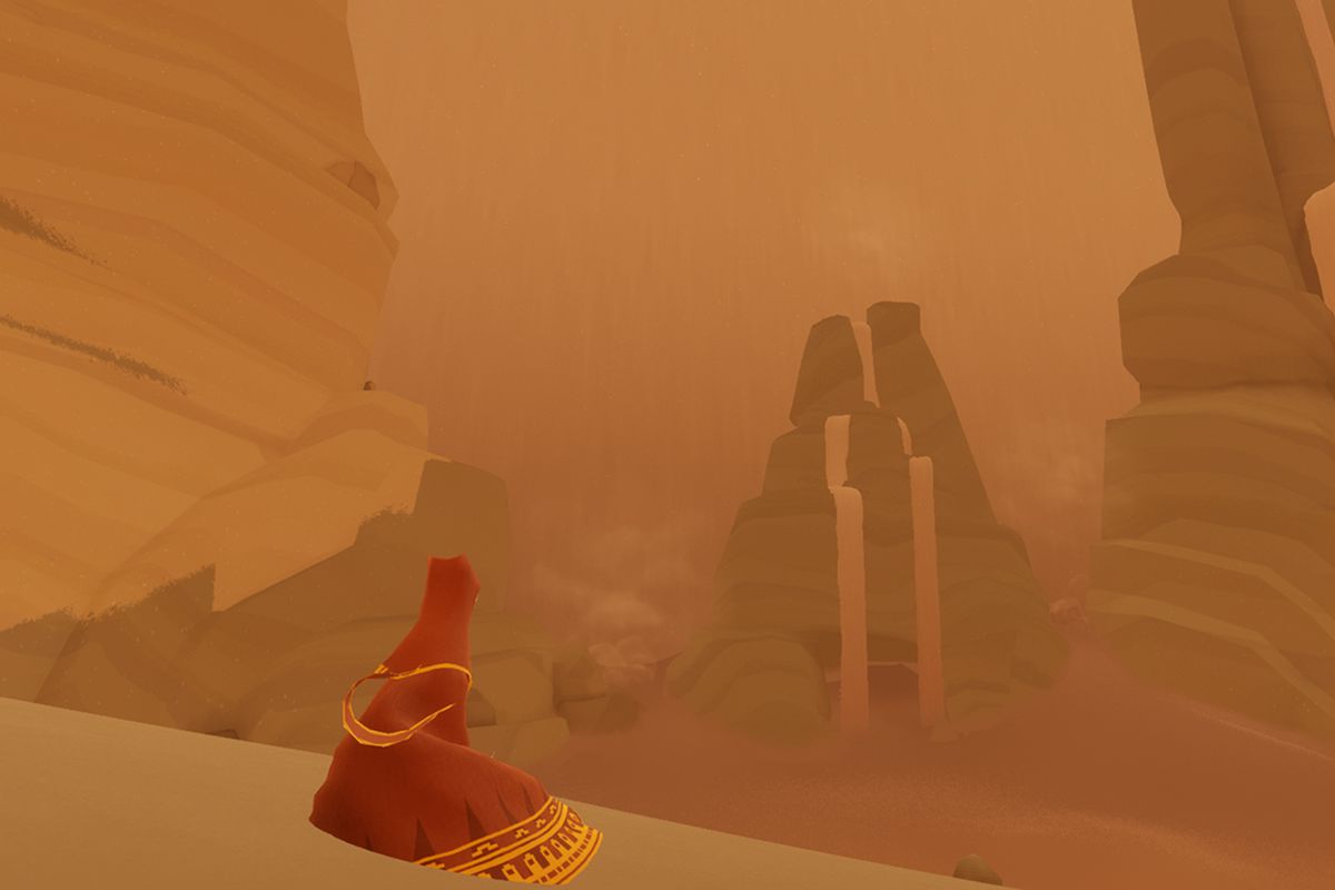 The traveler sits on a sand dune in a screenshot from Journey