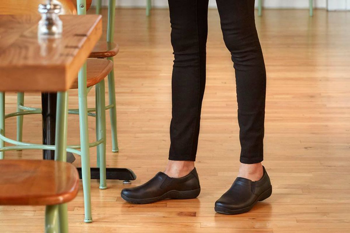 A woman working in a restaurant wearing Dansko shoes