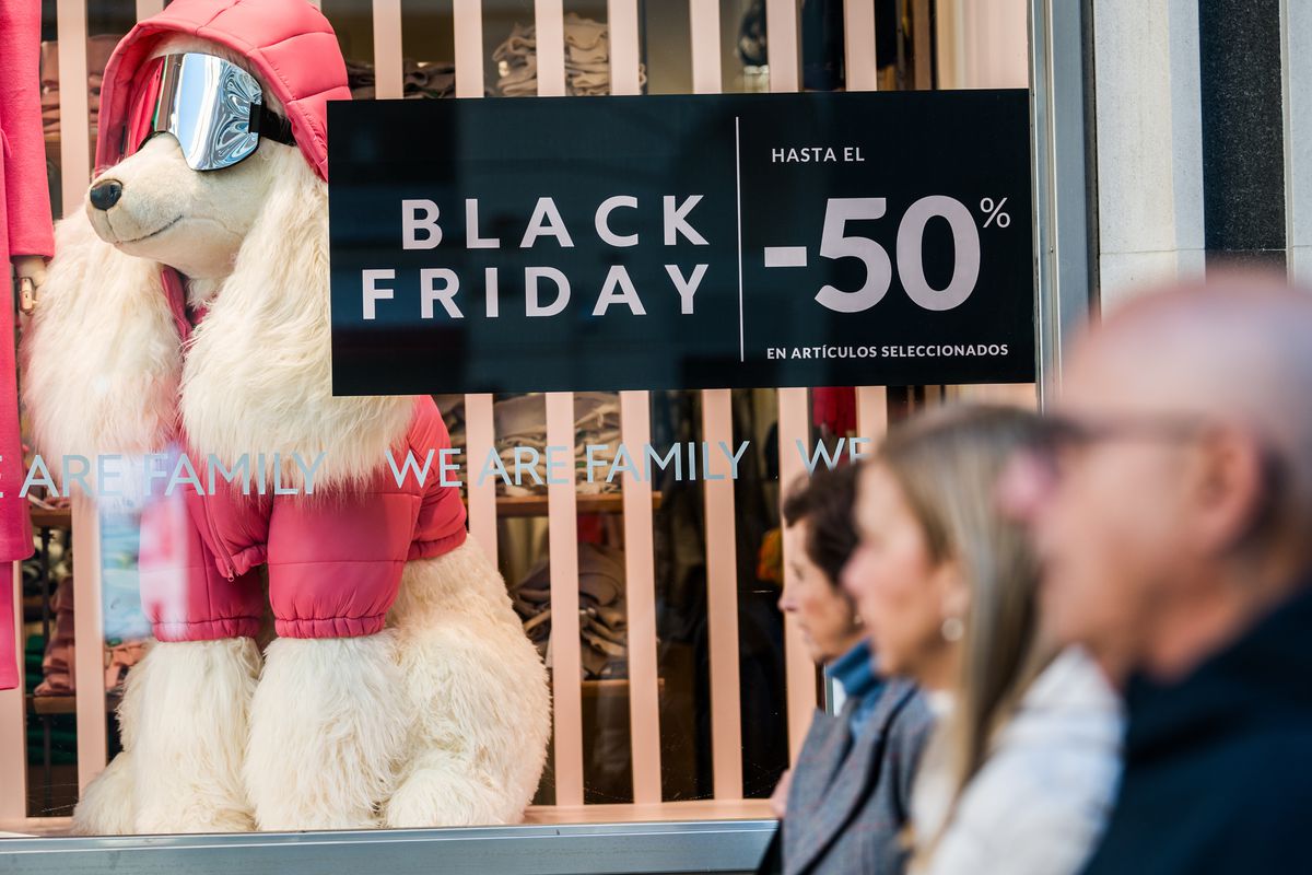 People walk past a shop displaying a Black Friday sales sign...