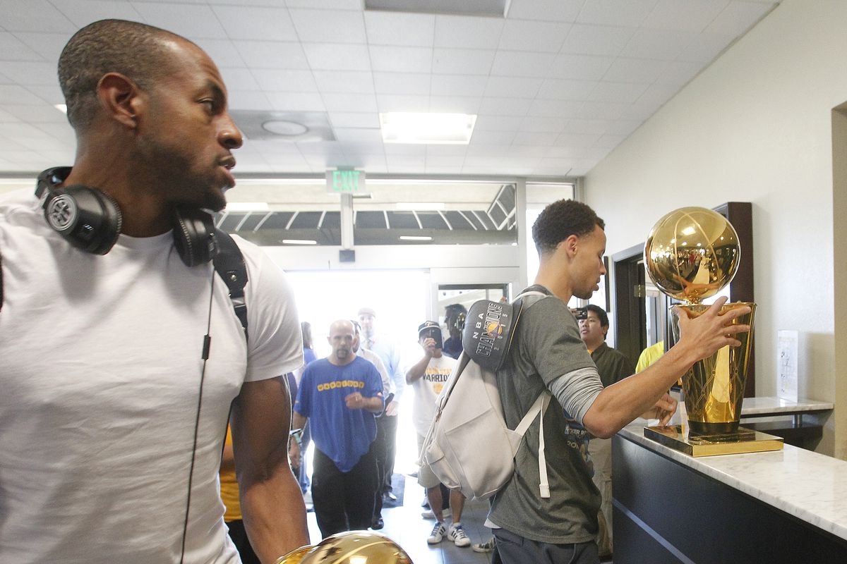 Golden State Warriors forward Andre Iguodala, right, carriers the trophy for being named MVP of the NBA championship and guard Stephen Curry, right, carries the Larry O’Brien NBA Championship Trophy after the team landed in Oakland, Calif., Wednesday, J