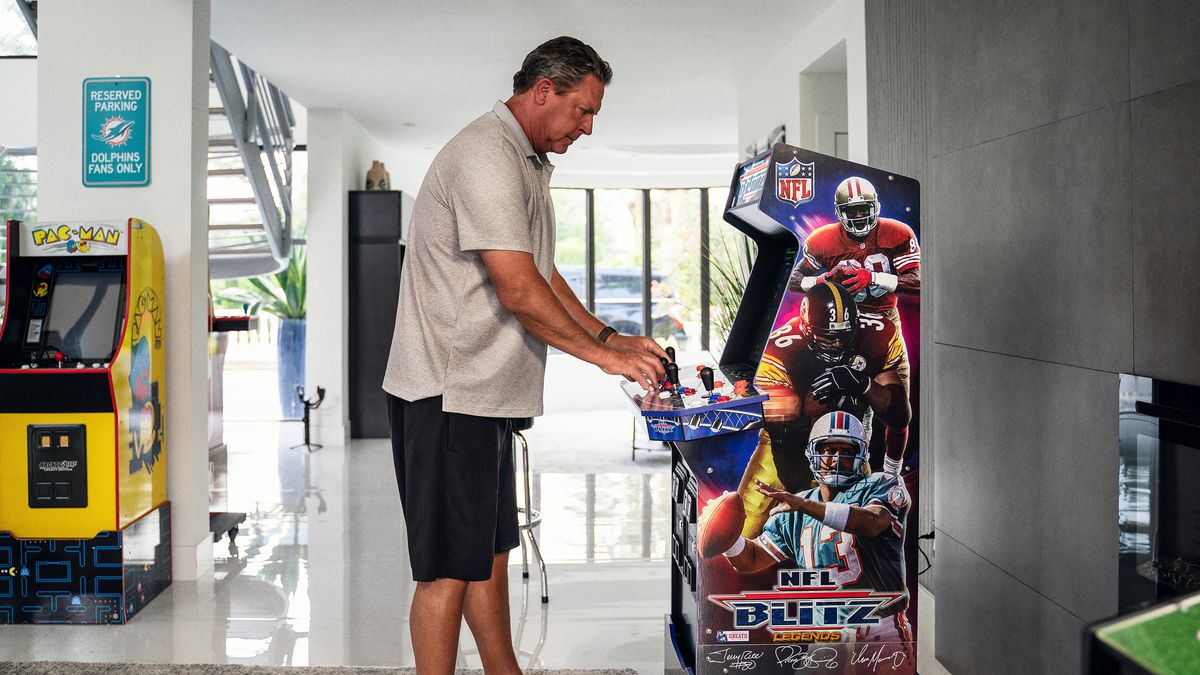 publicity shot of Dan Marino playing NFL Blitz Legends, an arcade cabinet re-release of three NFL Blitz from 1997 to 2000