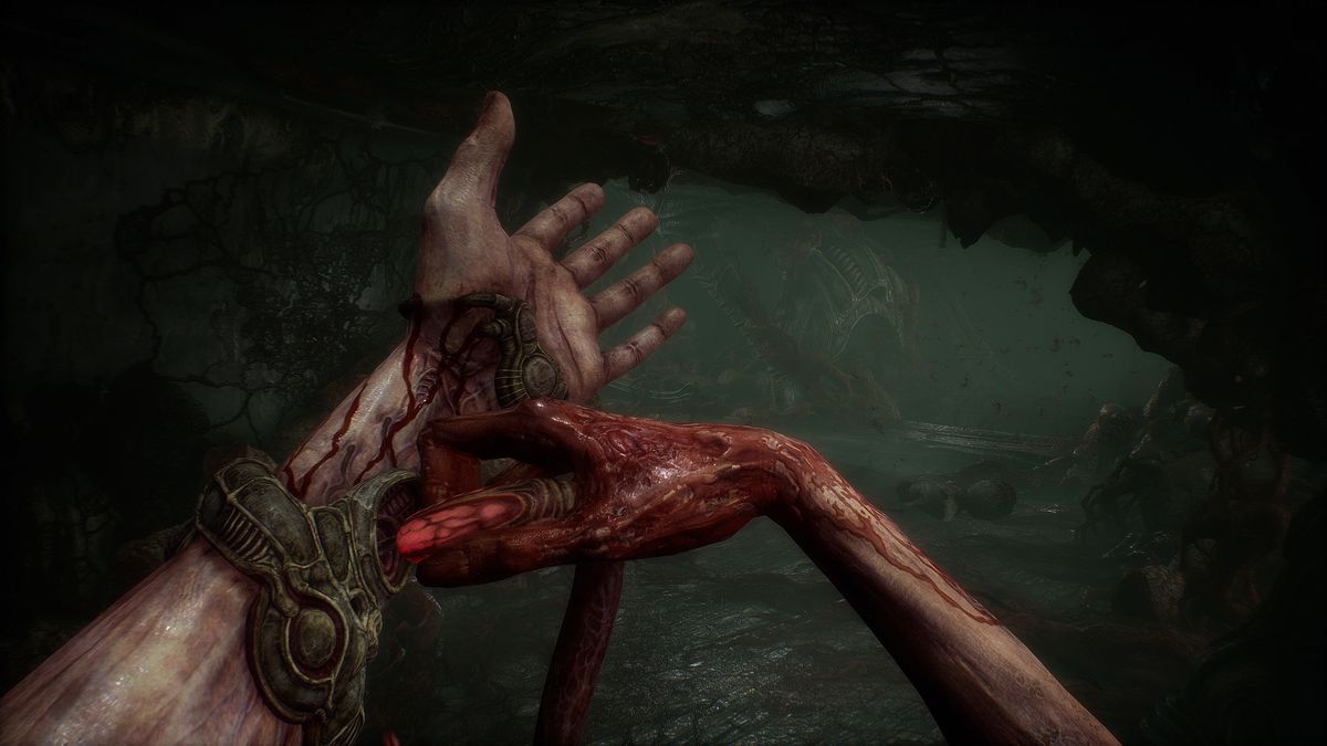 The player character in Scorn inserts a glowing red tube into its wrist, with blood staining both hands