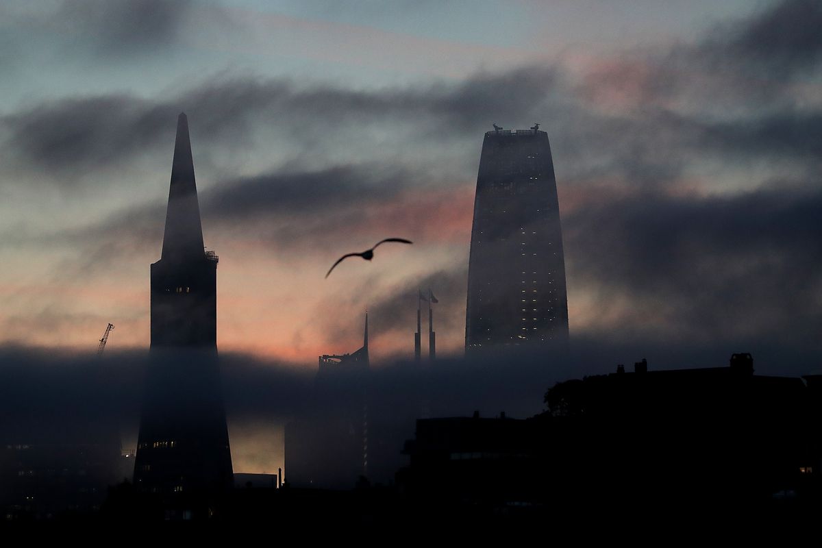 San Francisco Skyline through very dark fog, with the tops of Salesforce Tower and the Transamerica Pyramid visible.