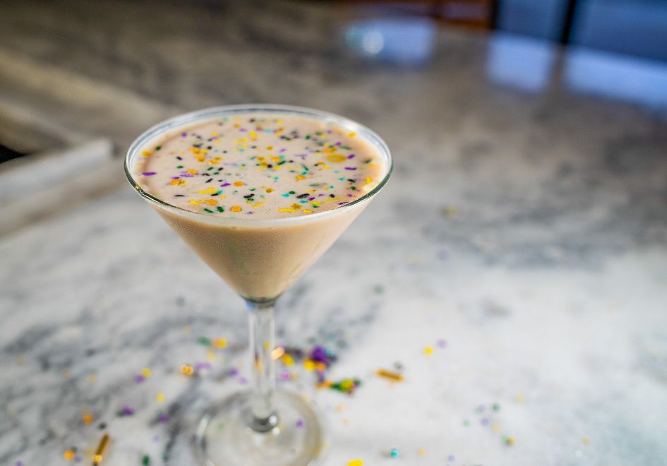A white martini with purple, green, and yellow sprinkles.