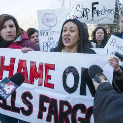 Liana Molina speaks as she and Deb Henry hold a "Shame on Wells Fargo" sign. Protesters chant and call for action against Wells Fargo Tuesday, April 23, 2013, at the Grand America Hotel in Salt Lake City during the bank's annual shareholders meeting.
