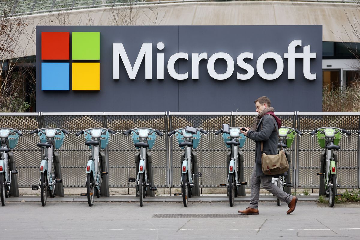 A man walks by some bicycles in front of a Microsoft building.