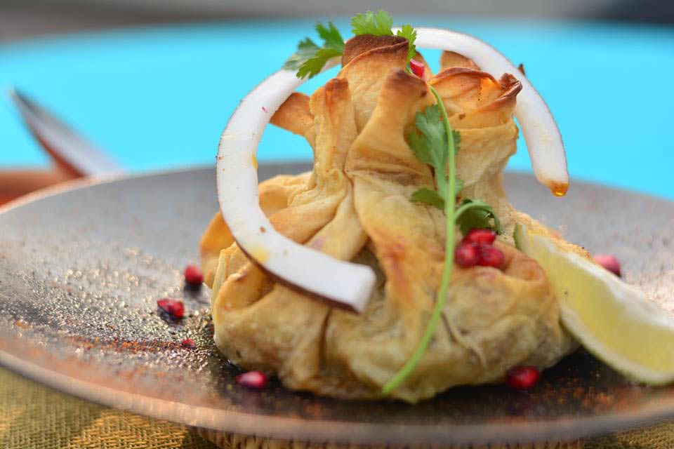 Flatbread formed into a dumpling garnished with herbs, onion and pomegranate seeds. 