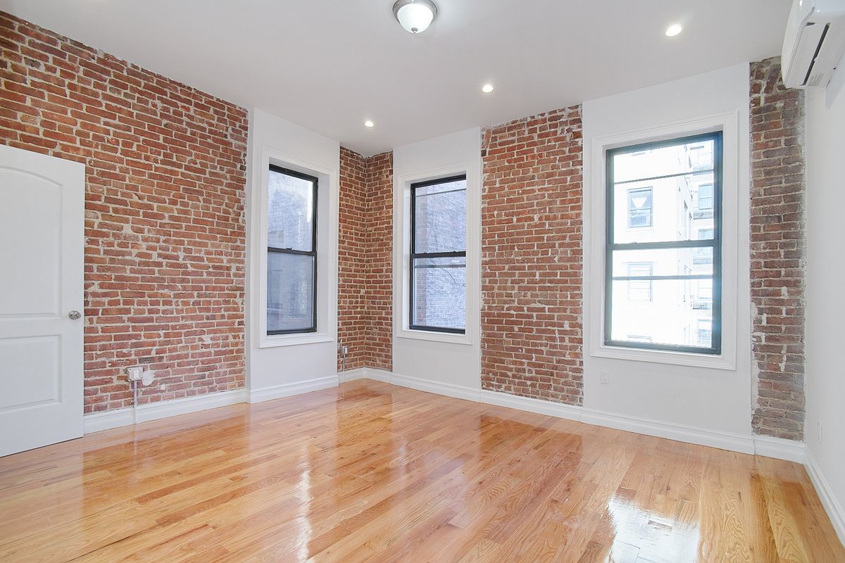 A living area with exposed brick and three windows.