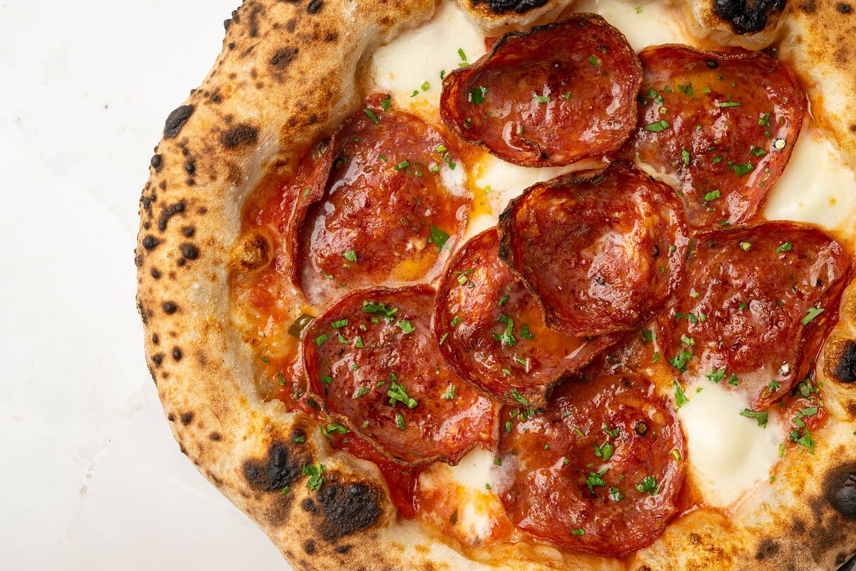 A top-down shot of a blistered pizza topped with tomato, cheese, and soppressata at Dante Beverly Hills.