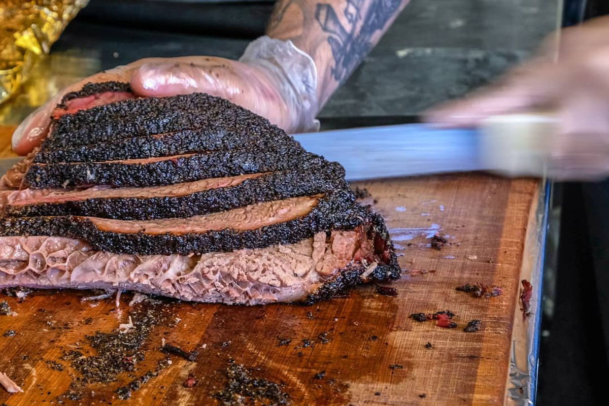 A chunk of beef being sliced on a butcher board. 
