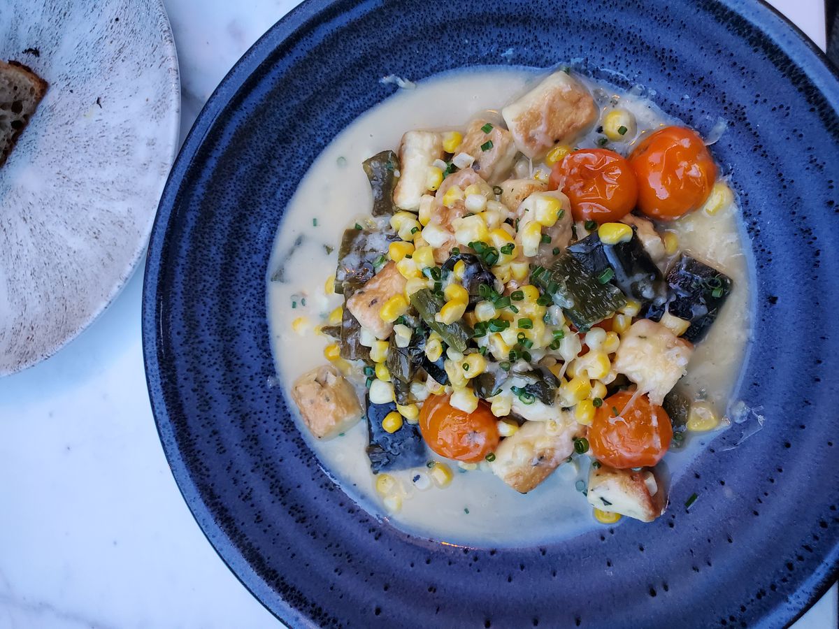 A bowl of gnocchi topped with vegetables.