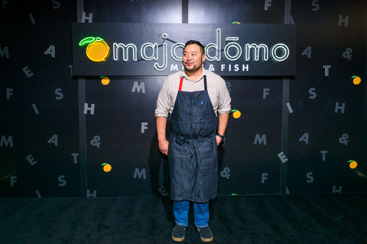 A chef stands in front of a sign