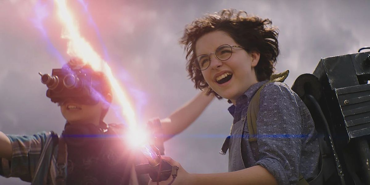 Mckenna Grace wearing goggles and Finn Wolfhard firing a proton pack in Ghostbusters: Afterlife.