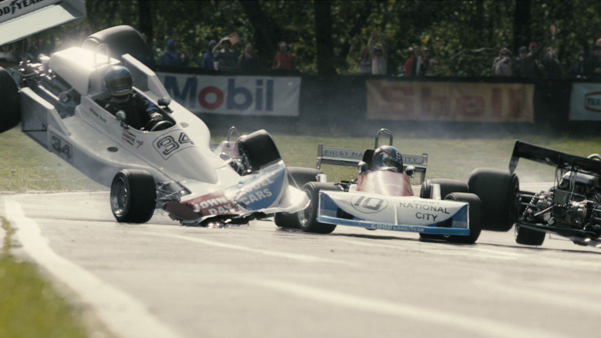 A race car careens along the curve of a race track as an adjacent race car crashes beside it.