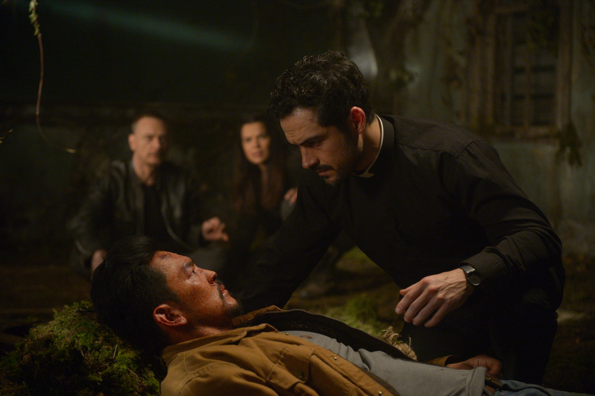 Alfonso Herrera leans over John Cho in the Exorcist TV show.