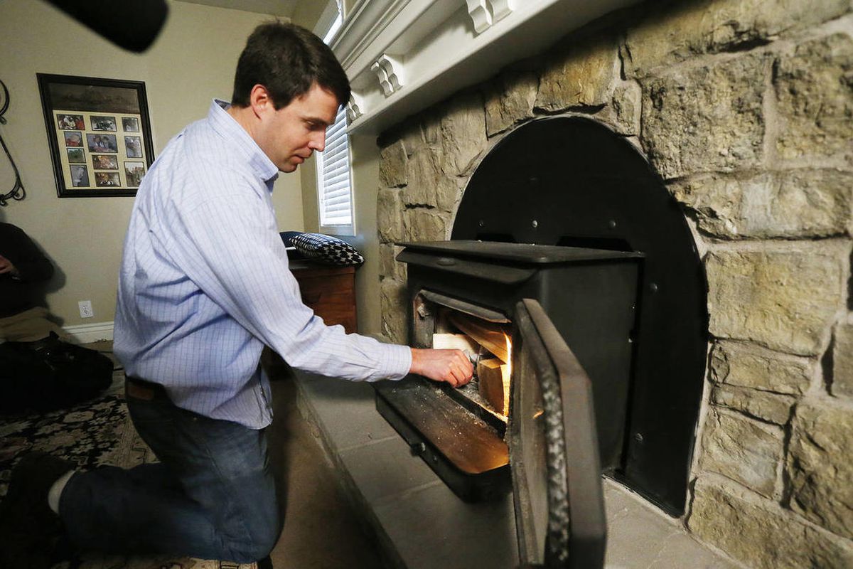 Joh Pohlman lights a fire in his wood-burning stove at his home in Sandy Wednesday, Jan. 14, 2015. Homeowners who use wood stoves or other solid fuel burning devices as their only source of heat must register with the Utah Department of Environmental Qual