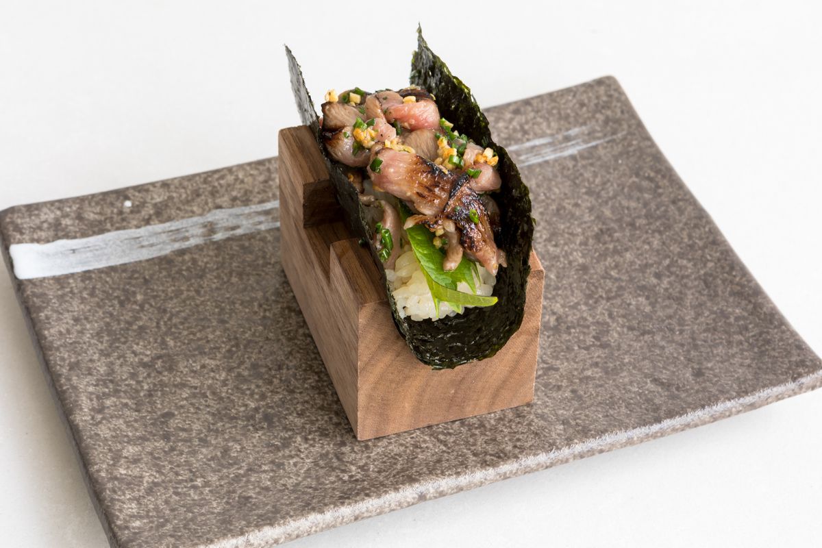 An A5 wagyu handroll with garlic chips and chives.