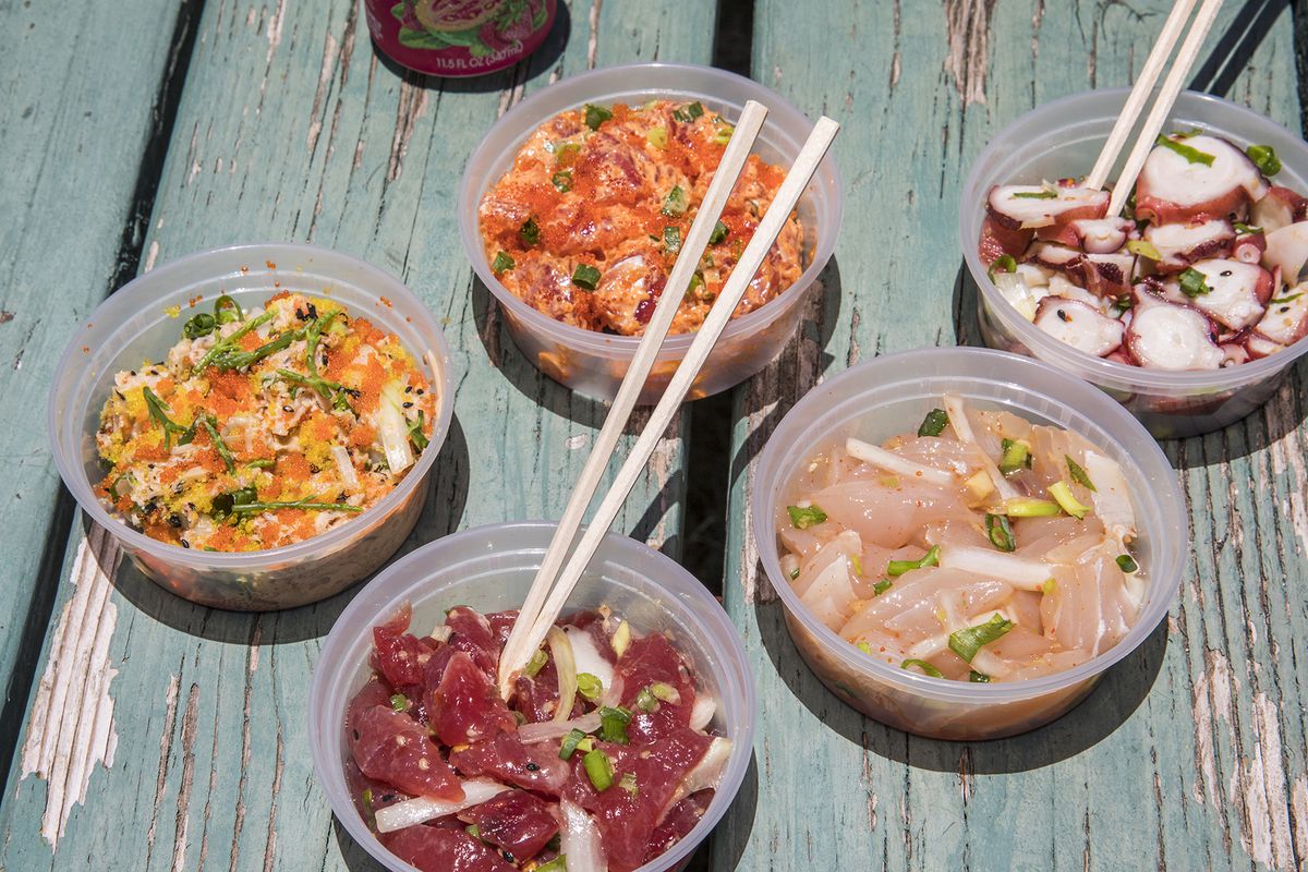 Five different kinds of poke in plastic containers arranged on a blue picnic table, with chopsticks sticking out of several containers. 
