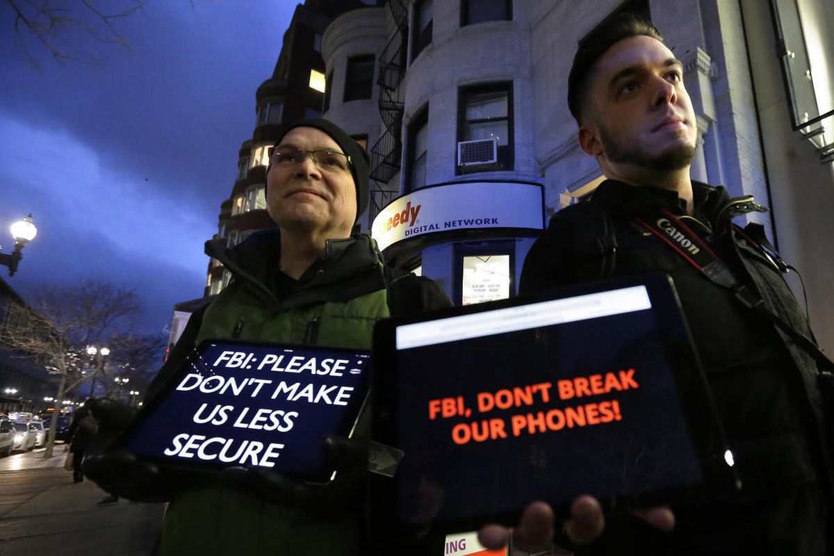 FILE - In this Tuesday, Feb. 23, 2016, file photo, demonstrators Peter Brockmann, of Northborough, Mass., left, and Chris Gladney, of Boston, right, display iPads with messages on their screens outside an Apple store in Boston. The FBI’s victory in breaki