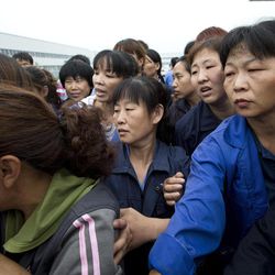 Workers try to push away journalists from the gate outside the Specialty Medical Supplies plant, where American Chip Starnes, a co-owner of the Florida-based plant, is being held hostage at the Jinyurui Science and Technology Park in Qiao Zi township of Huairou District, on the outskirts of Beijing, China Tuesday, June 25, 2013. 