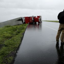 A passing motorist stops to look at a flipped truck in the aftermath of Hurricane Harvey Saturday, Aug. 26, 2017, north of Victoria, Texas.