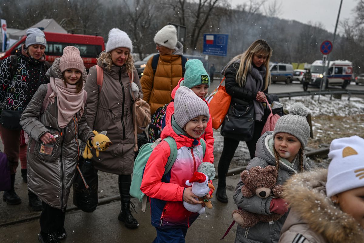خانواده‌های اوکراینی با کودکانی که در مرز لهستان از مسیر قطار عبور می‌کنند.