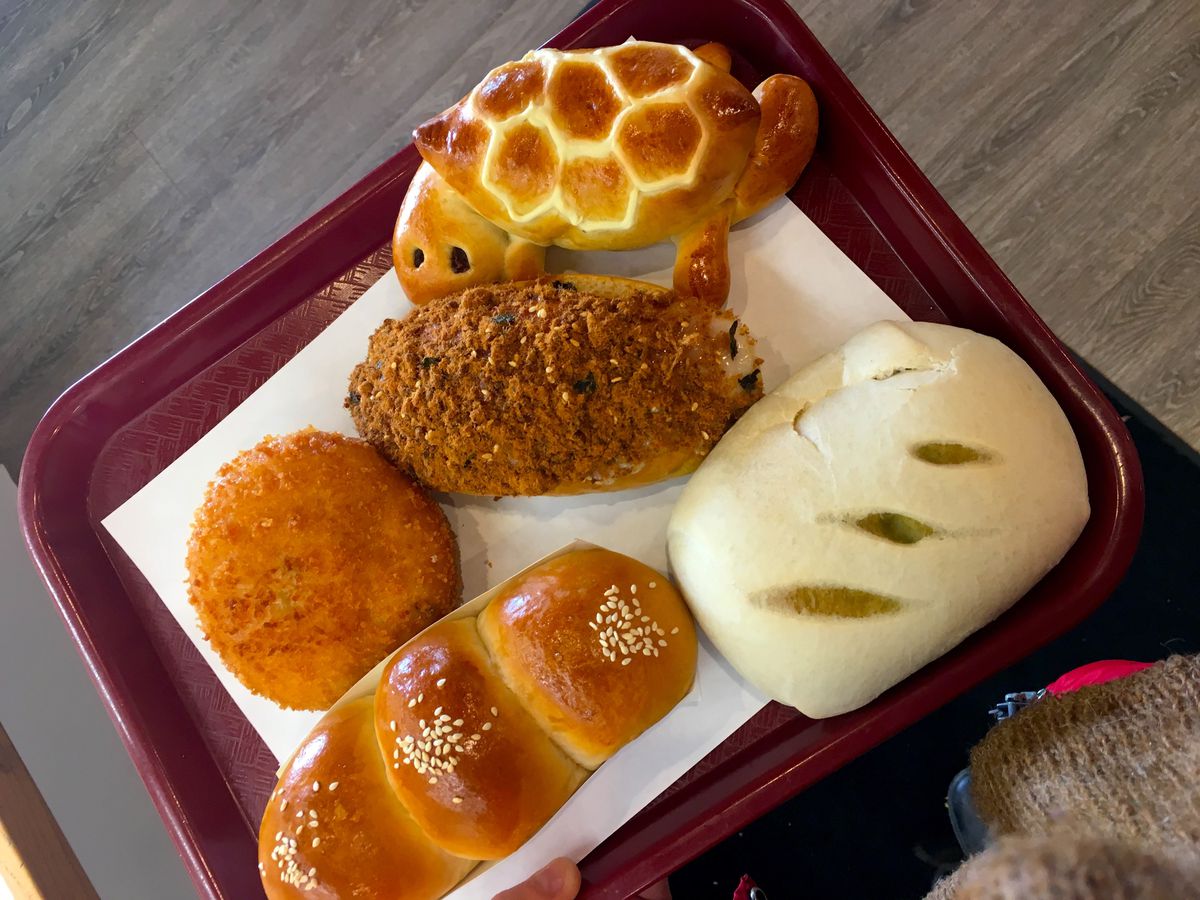 A variety of Japanese style breads on a red tray including one shaped like a turtle.
