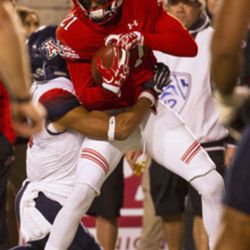 Utah wide receiver Tyrone Smith (21) secures the ball while being tackled by an Arizona player during the first half of an NCAA college football game in Salt Lake City on Saturday, Oct. 8, 2016. Arizona leads Utah 14-12 at halftime.  