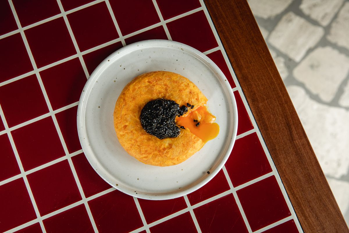 Spanish potato tortilla with caviar, on a red tile background at Decimo restaurant at The Standard London