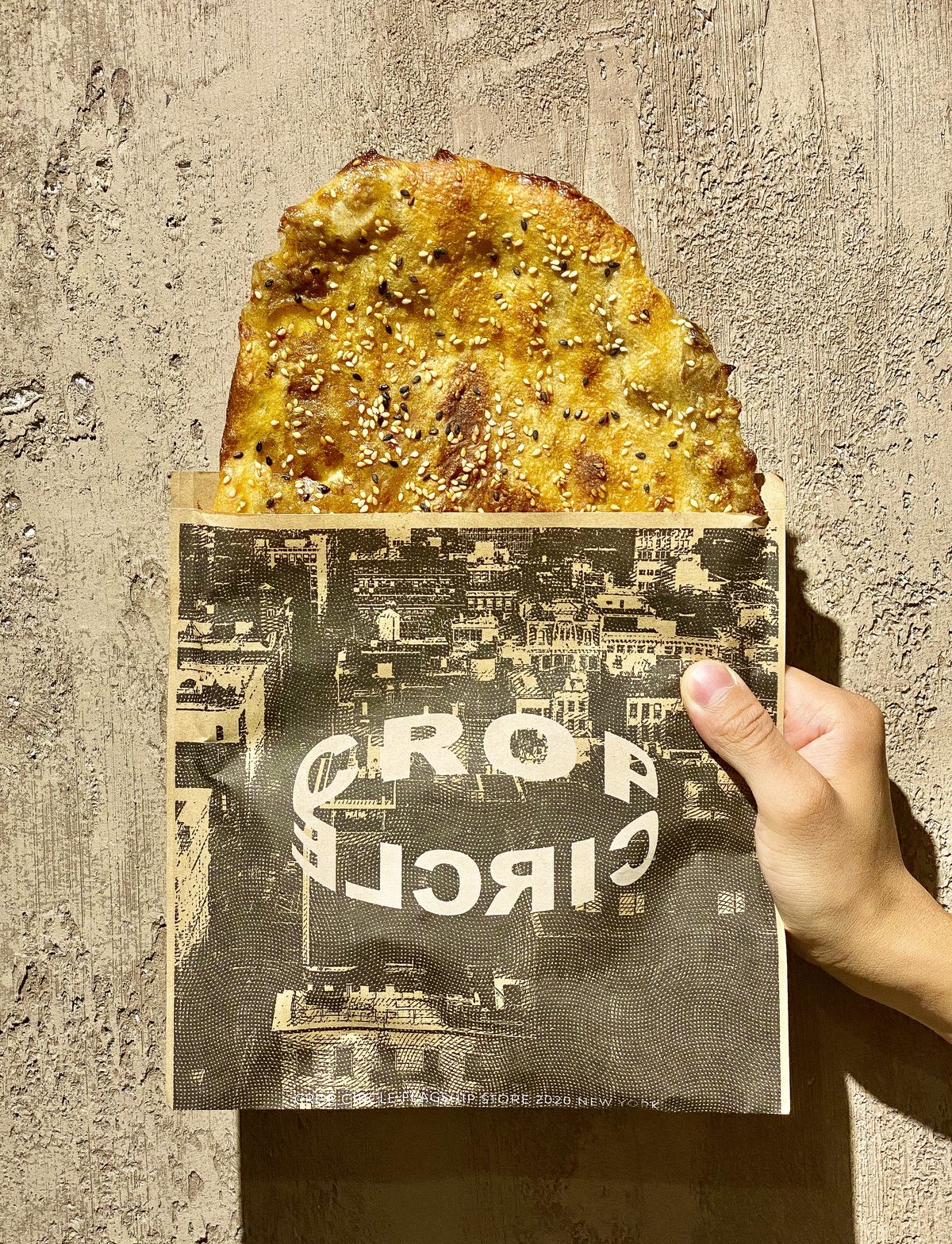 A hand holding a packet reading “Crop Circle” with a large flat bread placed inside