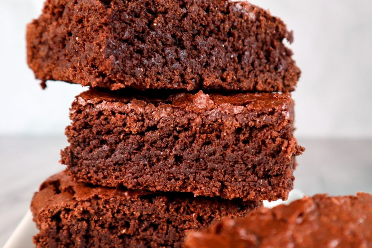 A stack of three pieces of brownies on a white plate.