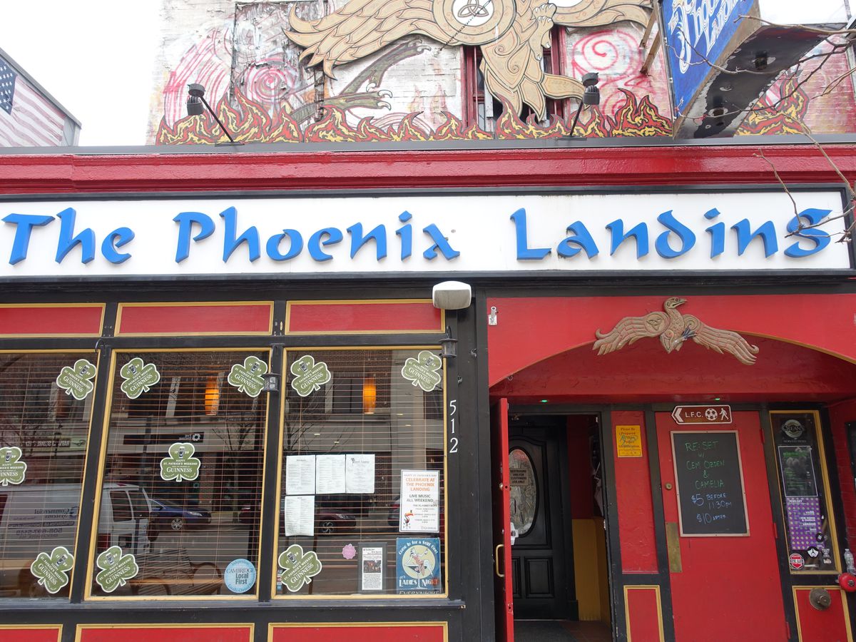 bright red exterior of a bar with a long white sign that says The Phoenix Landing in blue font