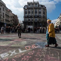 A man walks by solidarity messages written in chalk outside the stock exchange in Brussels on Tuesday, March 22, 2016. Explosions, at least one likely caused by a suicide bomber, rocked the Brussels airport and subway system Tuesday, prompting a lockdown of the Belgian capital and heightened security across Europe. At least 26 people were reported dead. 