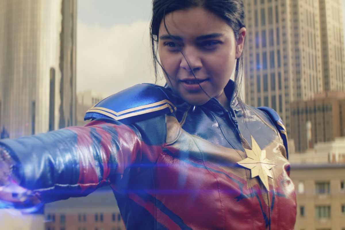 In Captain Marvel cosplay, Ms. Marvel holds out her hand, which is covered in glowing light.