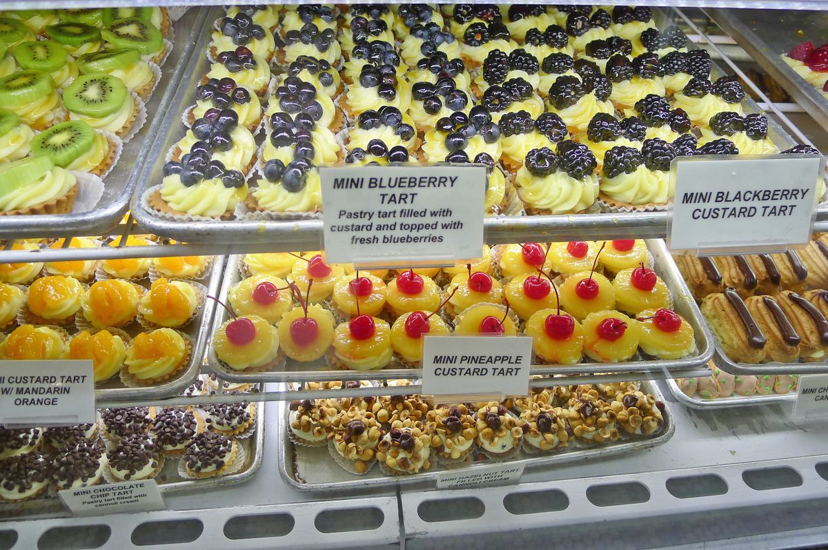 A glass case filled with miniature pastries topped with fruit.