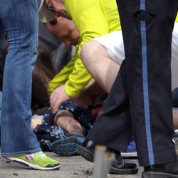 In this photo provided by The Daily Free Press and Kenshin Okubo, people help an injured person after an explosion at the 2013 Boston Marathon in Boston, Monday, April 15, 2013. Two explosions shattered the euphoria of the Boston Marathon finish line on Monday, sending authorities out on the course to carry off the injured while the stragglers were rerouted away from the smoking site of the blasts. 