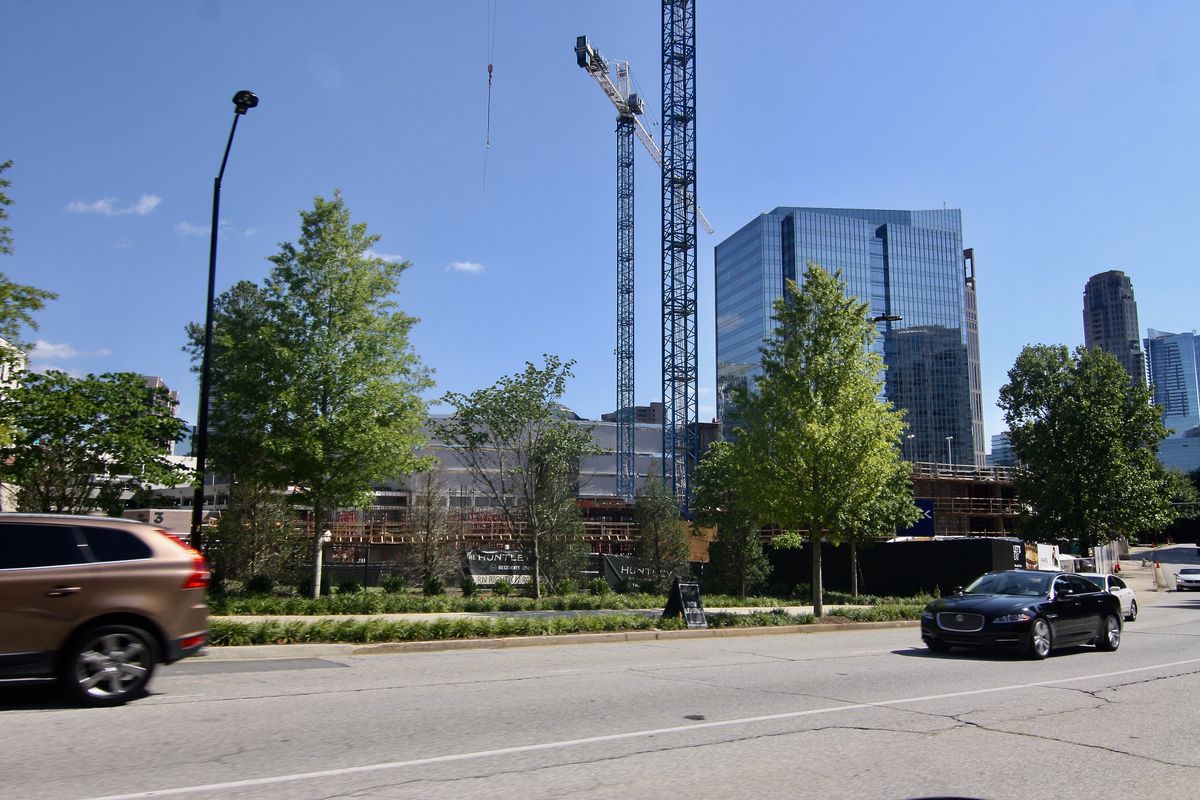 A construction scene in Buckhead with cars on a road in front. 