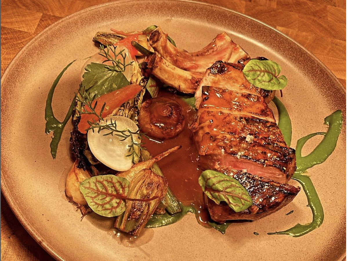 A pork chop with an orange glaze on a plate with a vegetable garnish.