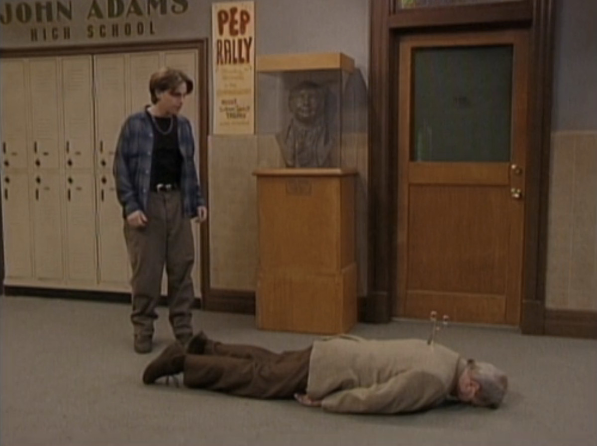 Shawn looks down at a dead Mr. Feeny with scissors sticking out of his back