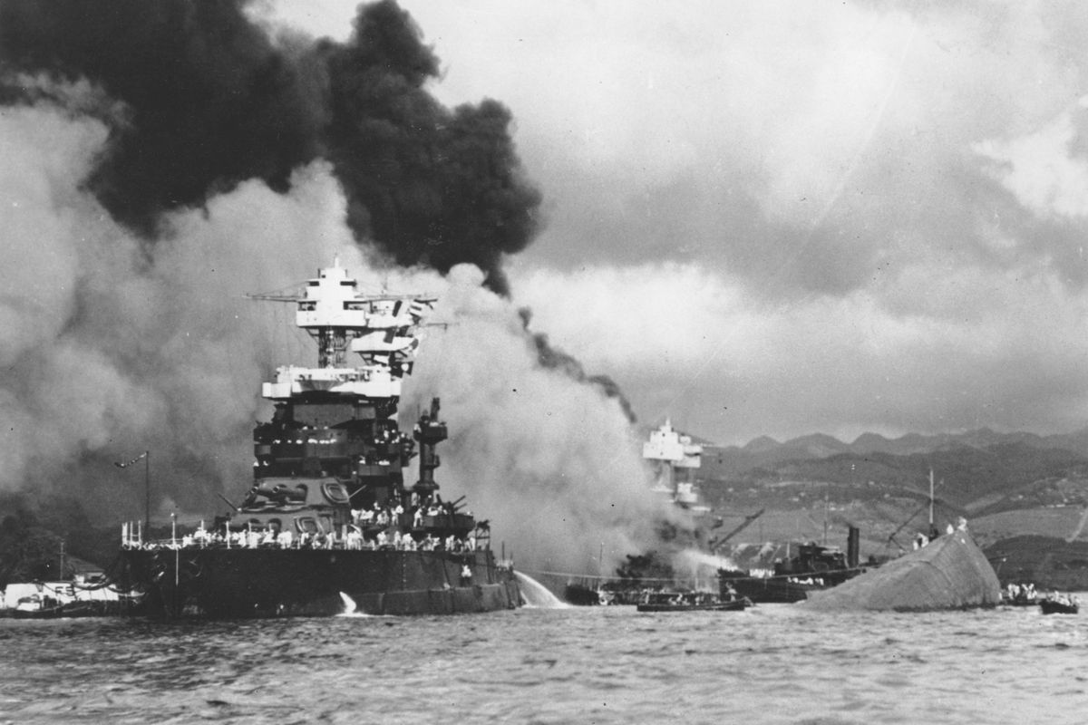 FILE - In this Dec. 7, 1941, file photo, part of the hull of the capsized USS Oklahoma is seen at right as the battleship USS West Virginia, center, begins to sink after suffering heavy damage, while the USS Maryland, left, is still afloat in Pearl Harbor, Oahu, Hawaii. Pearl Harbor survivors and World War II veterans are gathering in Hawaii this week to remember those killed in the Dec. 7, 1941 attack. Those attending will observe a moment of silence at 7:55 a.m., the minute the bombing began. The ceremony will mark the 80th anniversary of the attack that launched the U.S. into World War II. (U.S. Navy via AP, File) ORG XMIT: LA902