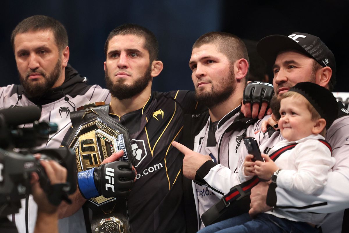 Islam Makhachev poses with Khabib Nurmagomedov after defeating Charles Oliveira to win the UFC LW title.