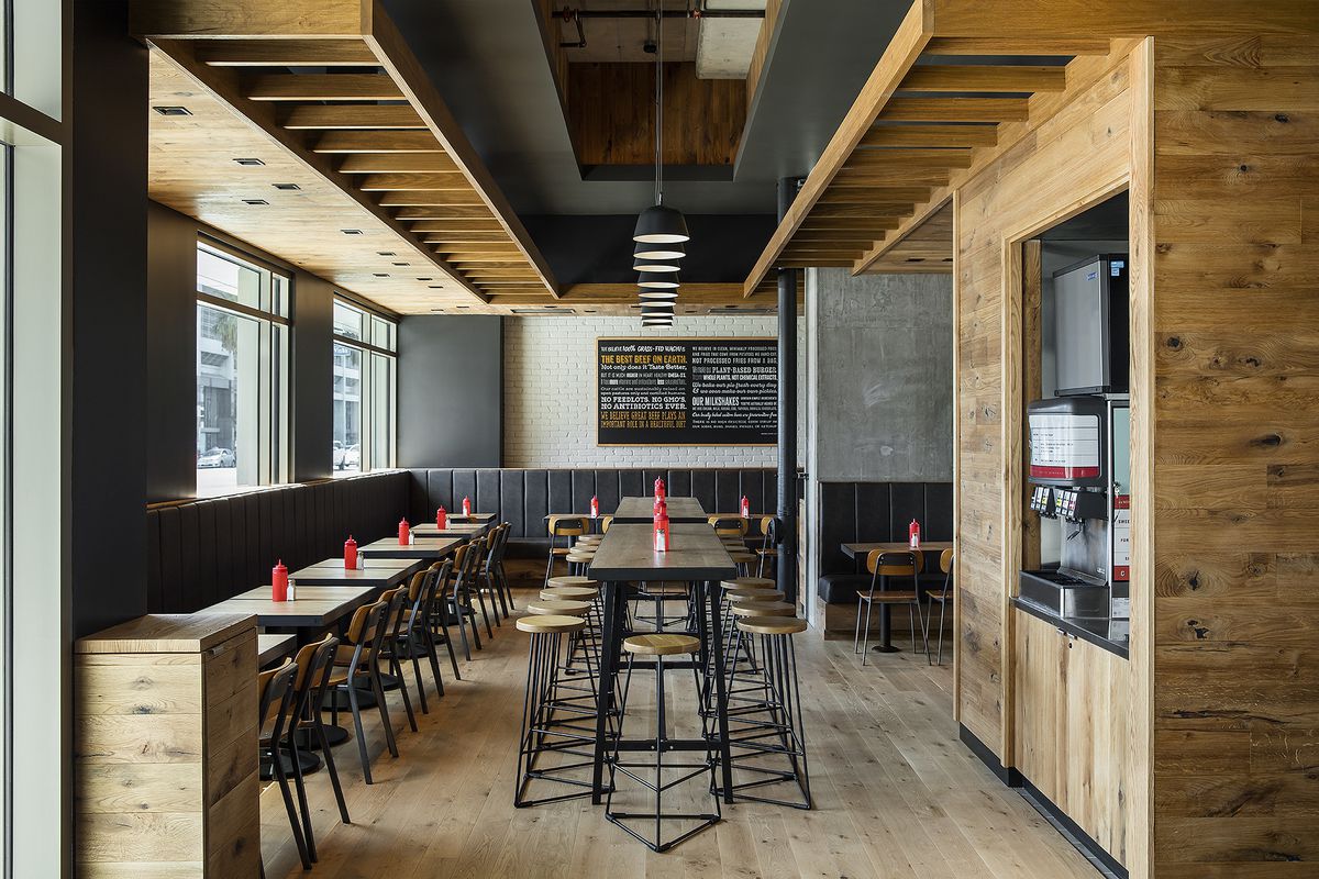 A well-lit wood-lined restaurant space with ketchup on every table.