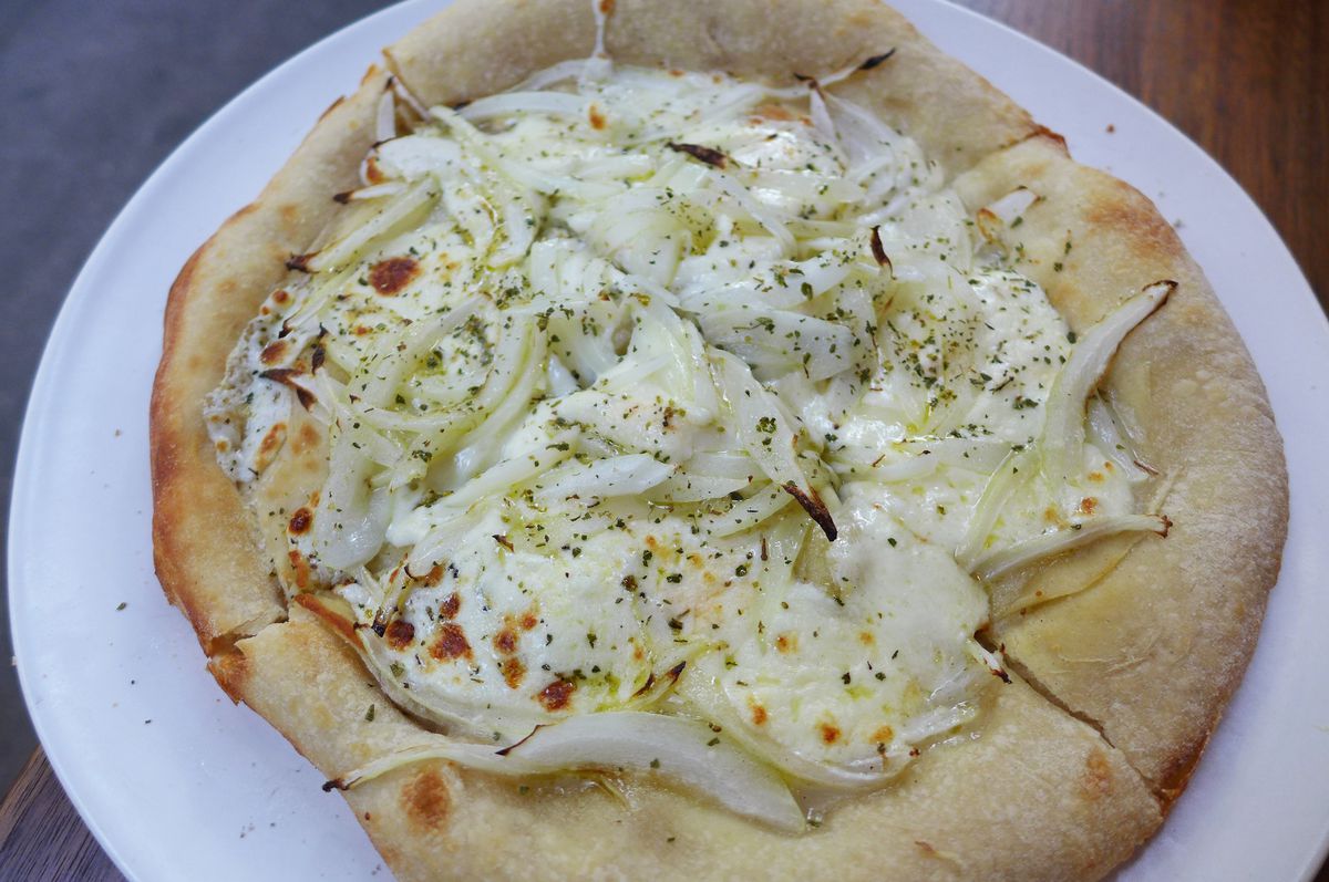 A round pie with no tomato sauce heaped with onions seen from above.
