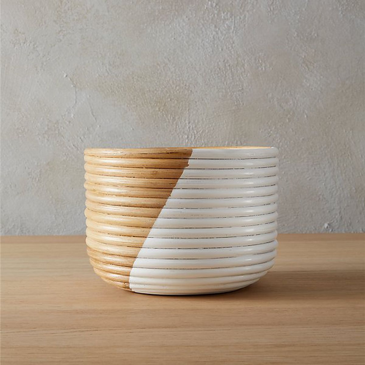 Rounded woven planter half painted in white. 