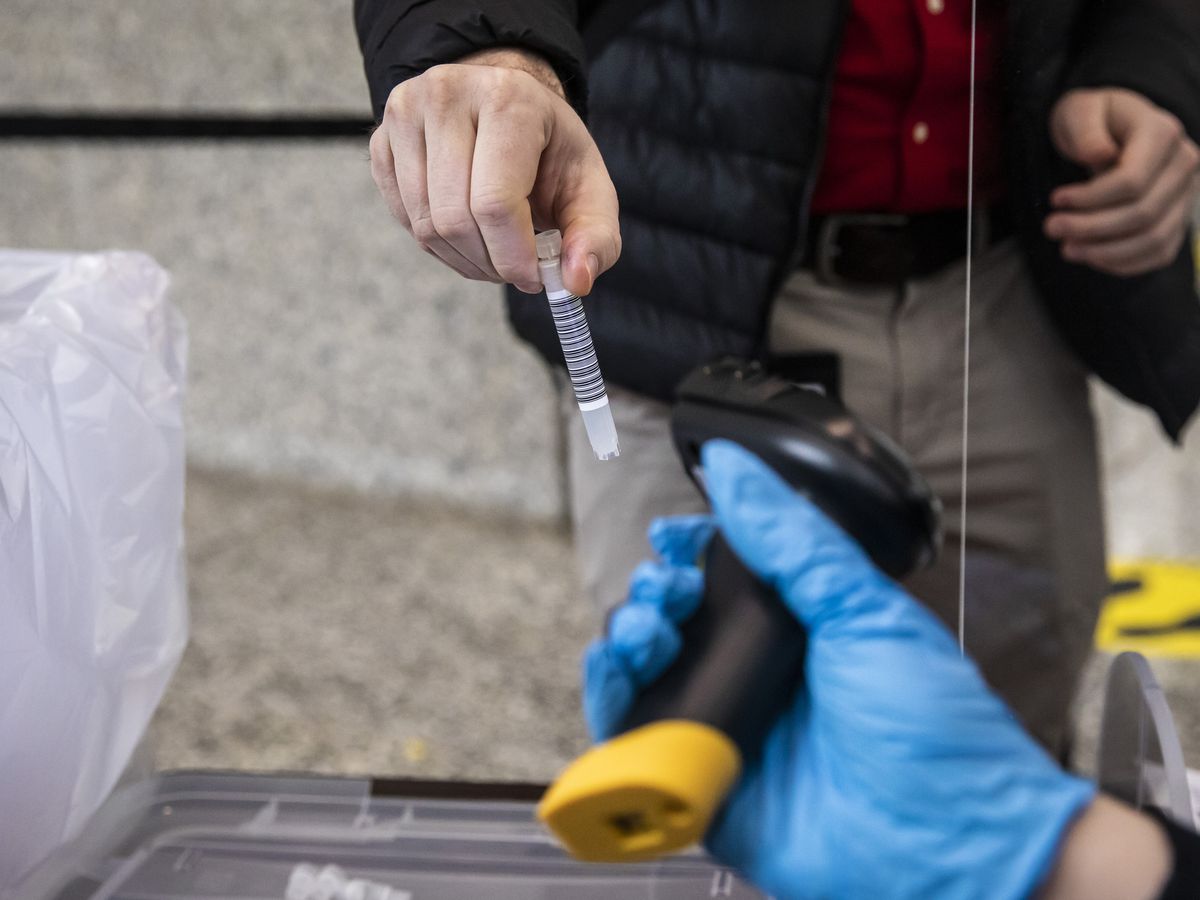 A person submits a saliva sample to test for COVID-19 at a free community testing site earlier this month at the Dirksen Federal Courthouse. Cases are declining sharply in Illinois, but deaths aren’t.