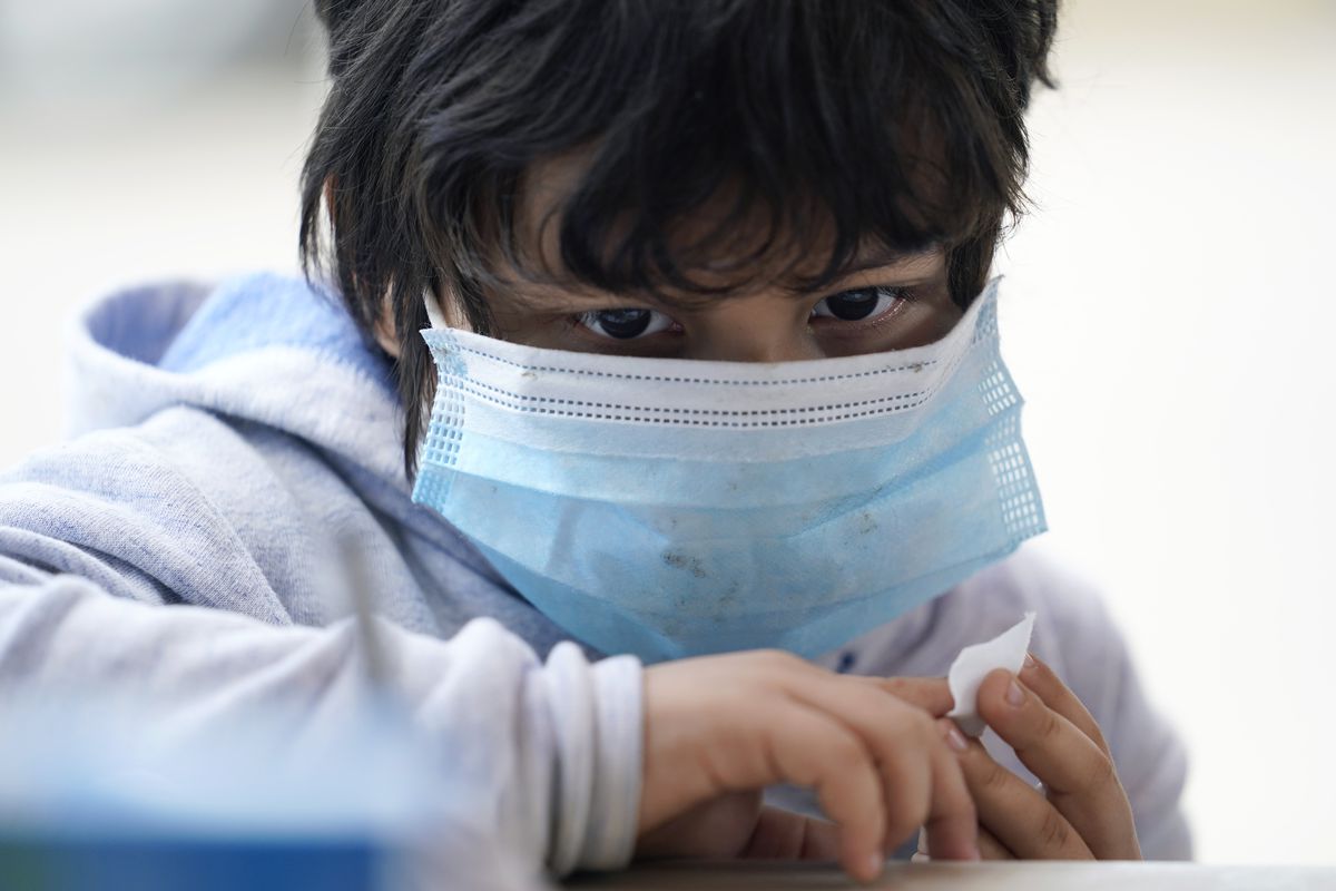 A young migrant seeking asylum in the U.S. holds a bandage on his finger after he was tested for COVID-19 antibodies at a clinic in Matamoros, Mexico, Nov. 18, 2020.