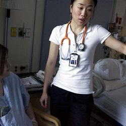 Nurse Minji Park checks an IV for patient Amber Stones at University Hospital. White tops will be mandatory for nurses.    