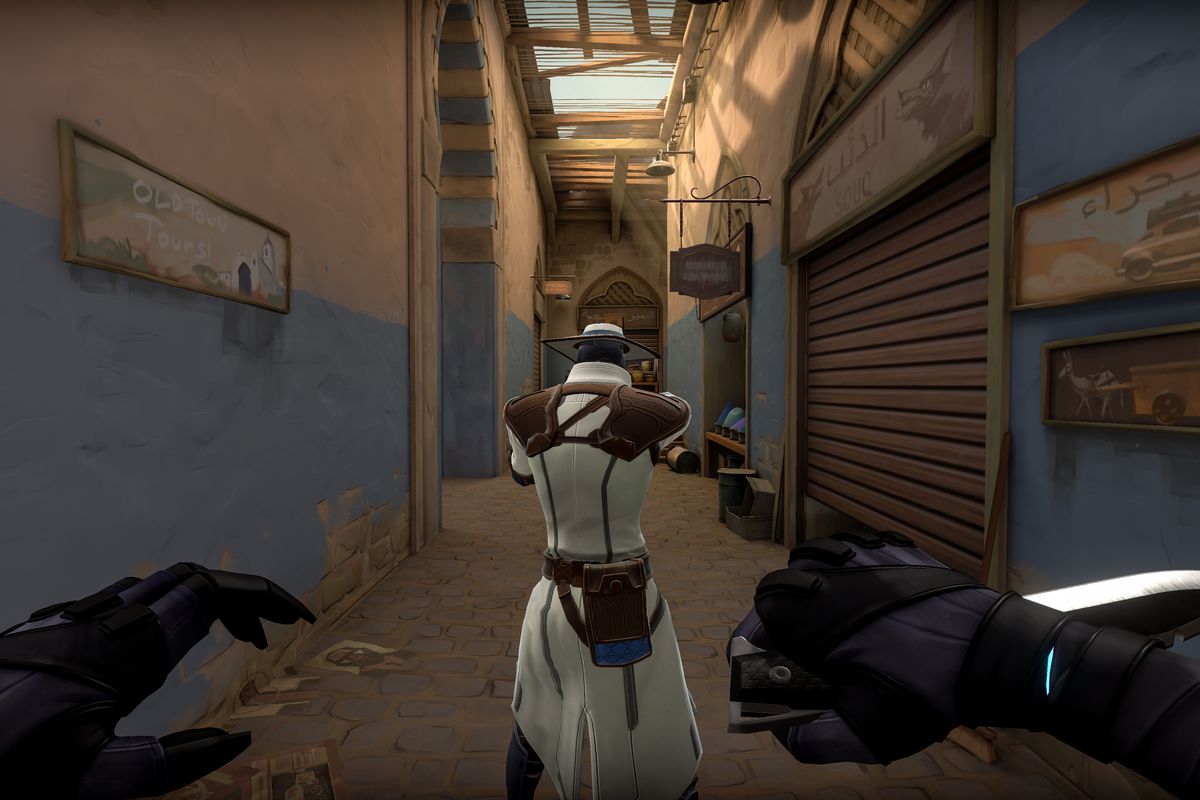 One player looks down a hallway in Valorant while another players sneaks up from behind